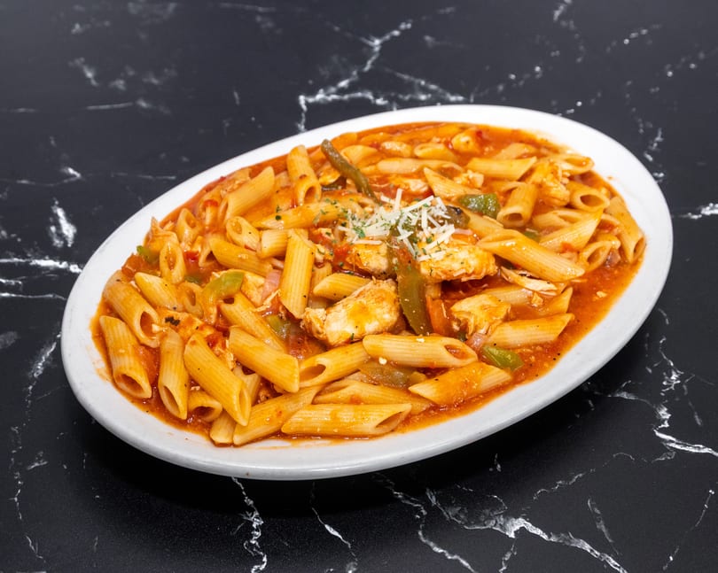 Penne pasta with chicken, green peppers, and red sauce, garnished with cheese and parsley.